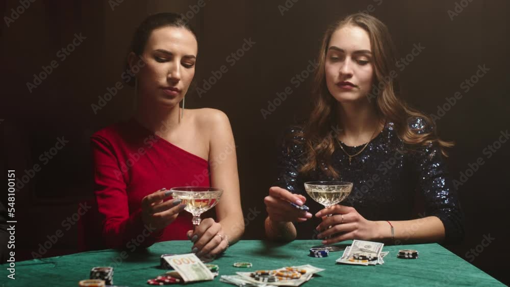 young women stare at their poker playing cards, make bets while playing in the casino. Entertainment industry and luxury lifestyle. The concept of gambling in the casino and poker. young women stare at their poker playing cards, make bets while playing in the casino. Entertainment industry and luxury lifestyle. The concept of gambling in the casino and poker.