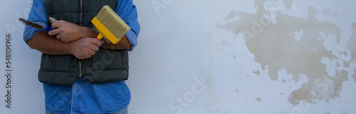 Smiling handyman holding brush and various tools showing the difference after fixing a house wall from humidity and mold. Horizontal banner 
