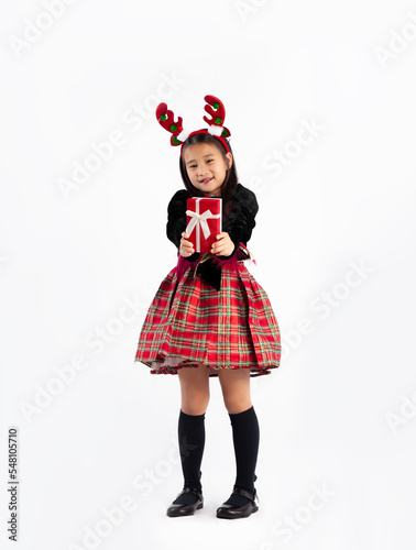Asian kid student girl in black and red Christmas theme costume holding and giving red present box standing full length white background. Merry Christmas.