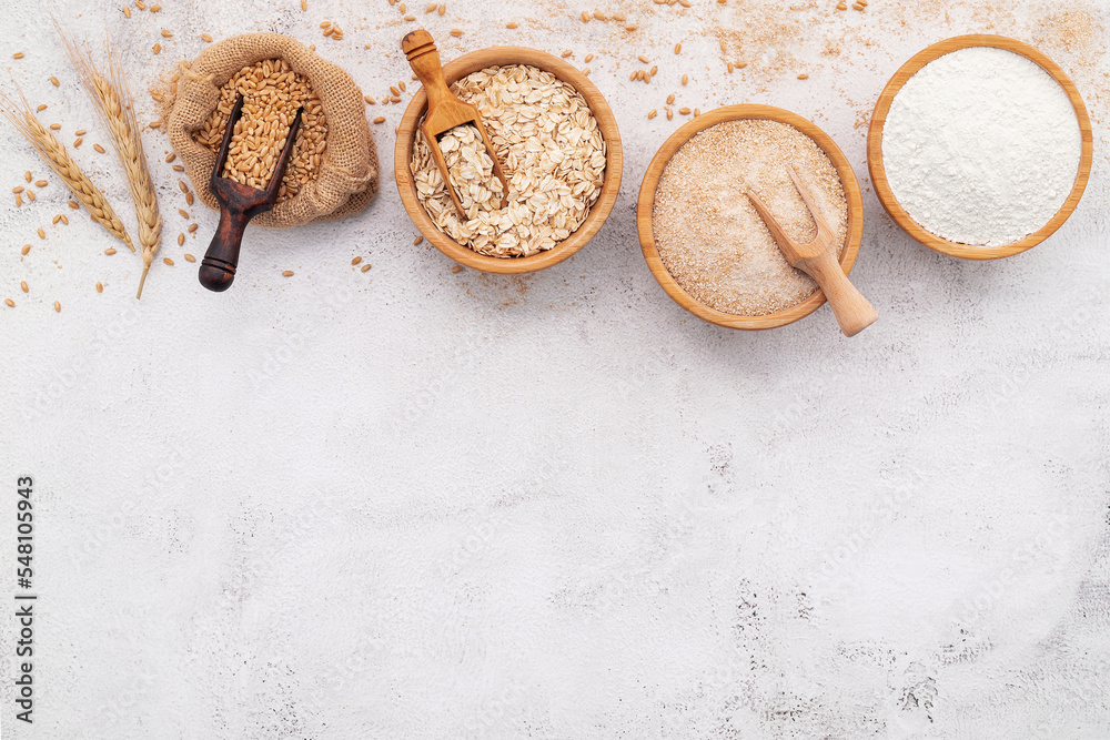 Wheat grains , brown wheat flour and white wheat flour in wooden bowl set up on white concrete background. Wheat grains , brown wheat flour and white wheat flour in wooden bowl set up on white concrete background.