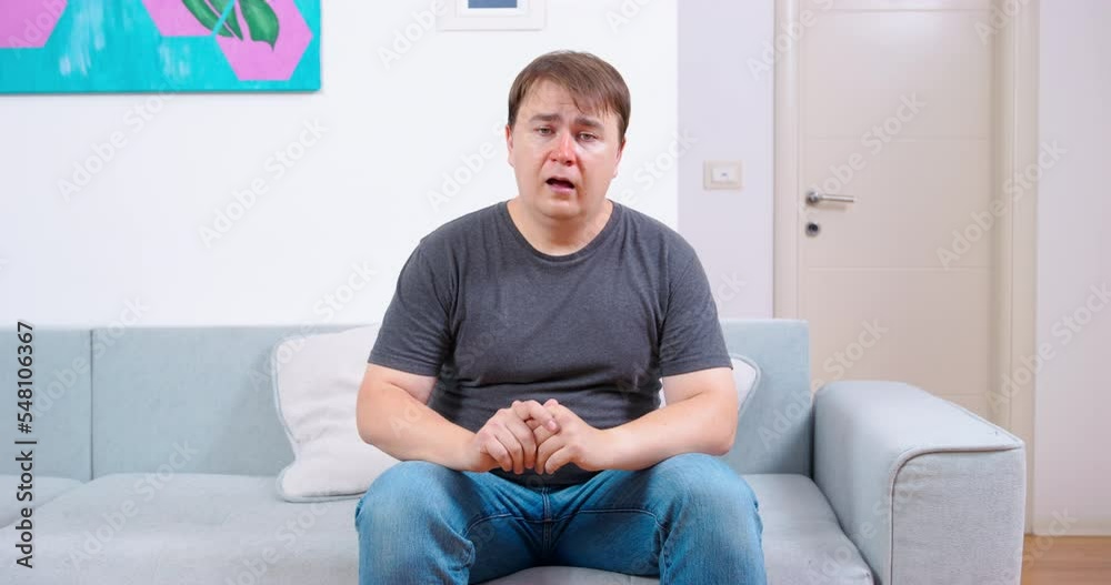 Sick exhausted man sits down on sofa sighs heavily ready for unpleasant conversation with doctor. Ambulance home consultation diagnosis of disease man with cold is waiting test result, nods nervously Sick exhausted man sits down on sofa sighs heavily ready for unpleasant conversation with doctor. Ambulance home consultation diagnosis of disease man with cold is waiting test result, nods nervously