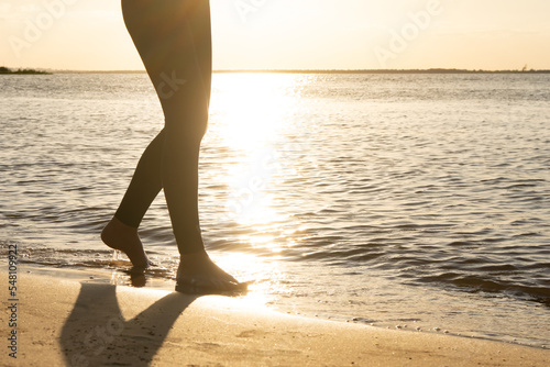 persona caminando descalza por la playa junto a la orilla del agua