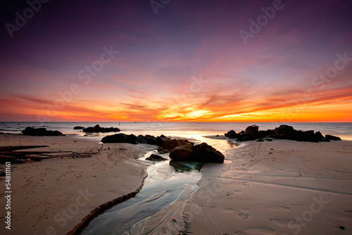 Beautiful Sunset on the beach, colourful scenery and small rock with green moss.