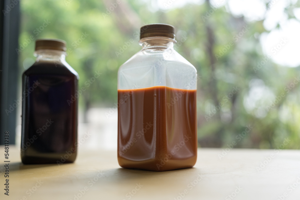 Bottle of cold beverage Thai milk tea, fresh, sweet and refreshment drink on table with against nature background. Bottle of cold beverage Thai milk tea, fresh, sweet and refreshment drink on table with against nature background.