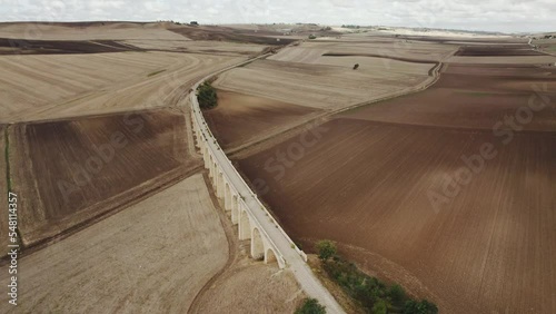 Drone flying in circulair motion around an old bridge with train tracks laying between farmfields in Italy in 4k photo