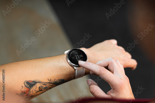 white index finger of right hand pointing a clock on tattooed left arm of young caucasian woman