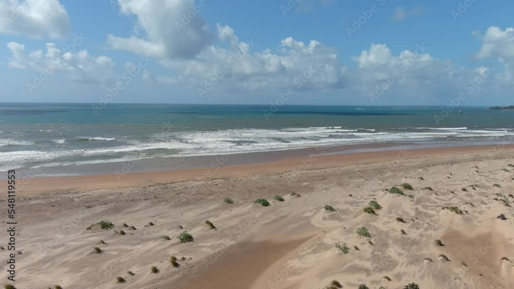 descending drone images to a beautiful large beach with light brown sand on a calm ocean descending drone images to a beautiful large beach with light brown sand on a calm ocean