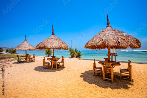 Fototapeta Naklejka Na Ścianę i Meble -  Beautiful tropical beach in kuta Lombok with wooden chair and sunbeds/ umbrella