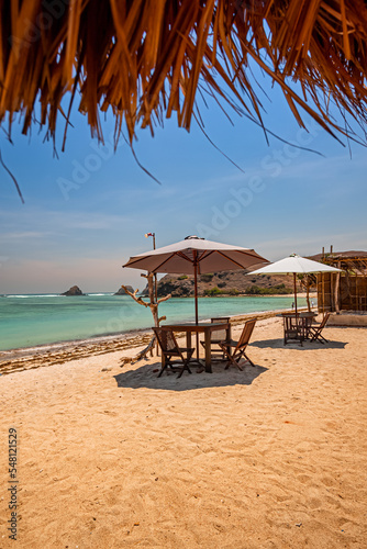 Beautiful tropical beach in kuta Lombok with wooden chair and sunbeds/ umbrella