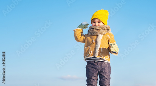 Child boy throwing snowball in winter outdoor. Happy child with snowball on snow background.
