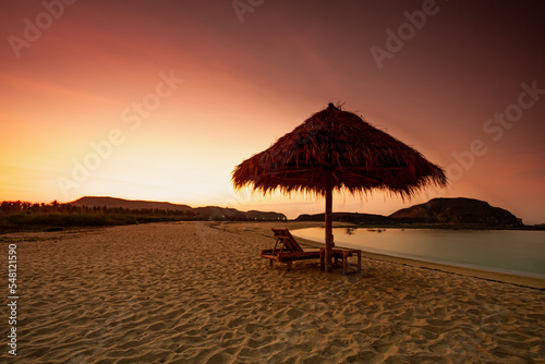 Beautiful tropical beach in kuta Lombok with wooden chair and sunbeds/ umbrella