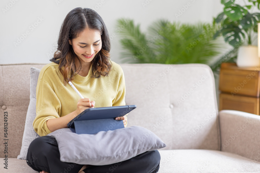 Remote learning concept. Happy Indian Asian Girl studying online, sitting on sofa with teblet at home. Indian teenager in Islamic headscarf using tablet, doing assignment, communicating to teacher, Remote learning concept. Happy Indian Asian Girl studying online, sitting on sofa with teblet at home. Indian teenager in Islamic headscarf using tablet, doing assignment, communicating to teacher,