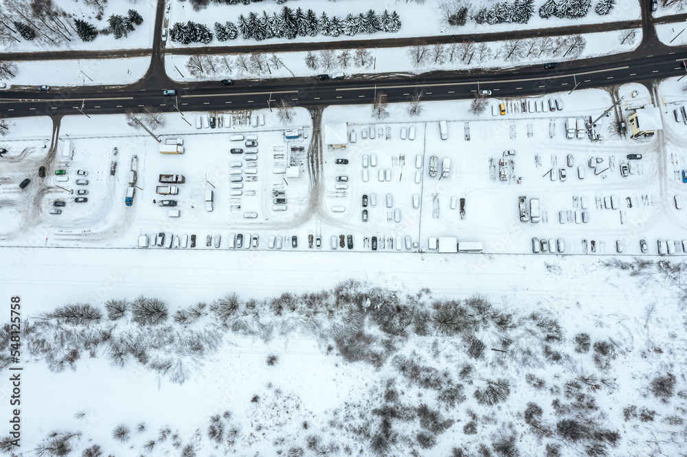 parking lot with snow-covered cars near residential area in wintertime. aerial top view.