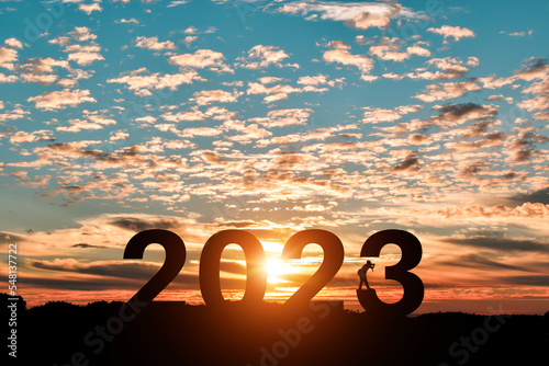 Silhouette of photographer taking photos in 2023 years at sunrise or sunset background. Idea for happy new year 2022.