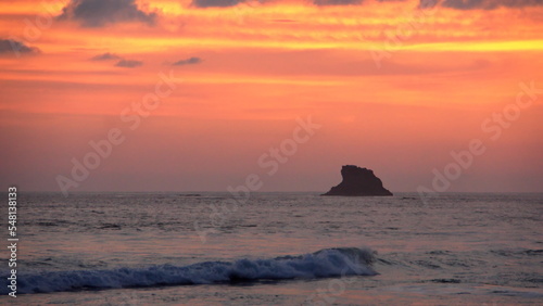 Sunset silhouetting a rocky islet at the beach in Zipolite  Mexico