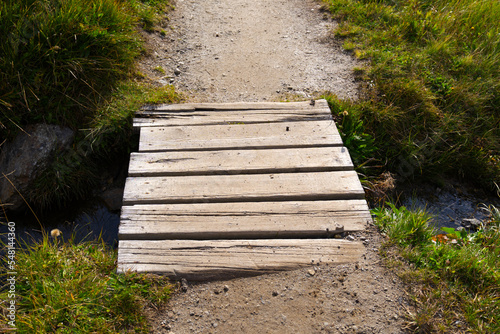 Hiking trail with scenic landscape at region Oberalppass Surselva with wooden bridge on a blue cloudy late summer day. Photo taken September 5th, 2022, Oberalppass, Switzerland.