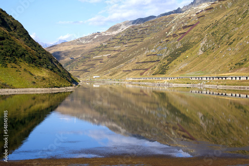 Railway station Oberalppass with lake and reflections of mountain panorama on a sunny late summer day. Photo taken September 5th, 2022, Oberalppass, Switzerland. photo