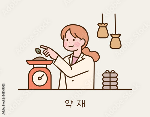 A traditional Korean doctor is weighing herbal medicines on a scale. She has her herbal pouch by her side.