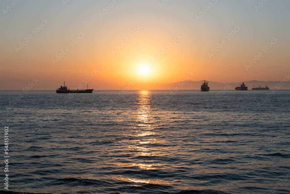 Beautiful orange sunset over the sea with a silhouettes of ships and soft selective focus. Beauty of nature concept