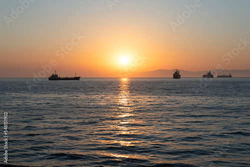 Beautiful orange sunset over the sea with a silhouettes of ships and soft selective focus. Beauty of nature concept