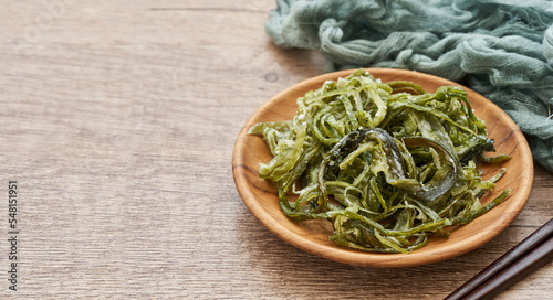 heap of fresh Korean salted seaweed salad stem side dish or Miyeok Julgi Bokkeum in wood bowl on wooden table background. Laminaria or Kelp Seaweed stem                                              photo