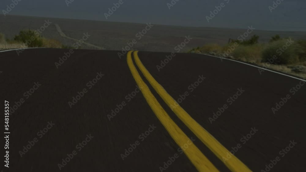 Moving shot along double yellow line on paved two lane road in California desert
