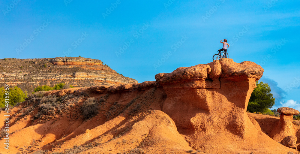 Woman on mountain bike on red rock canyon- freedom,  travel,  sport concept ( sierra de armantes,  aragon in Spain)