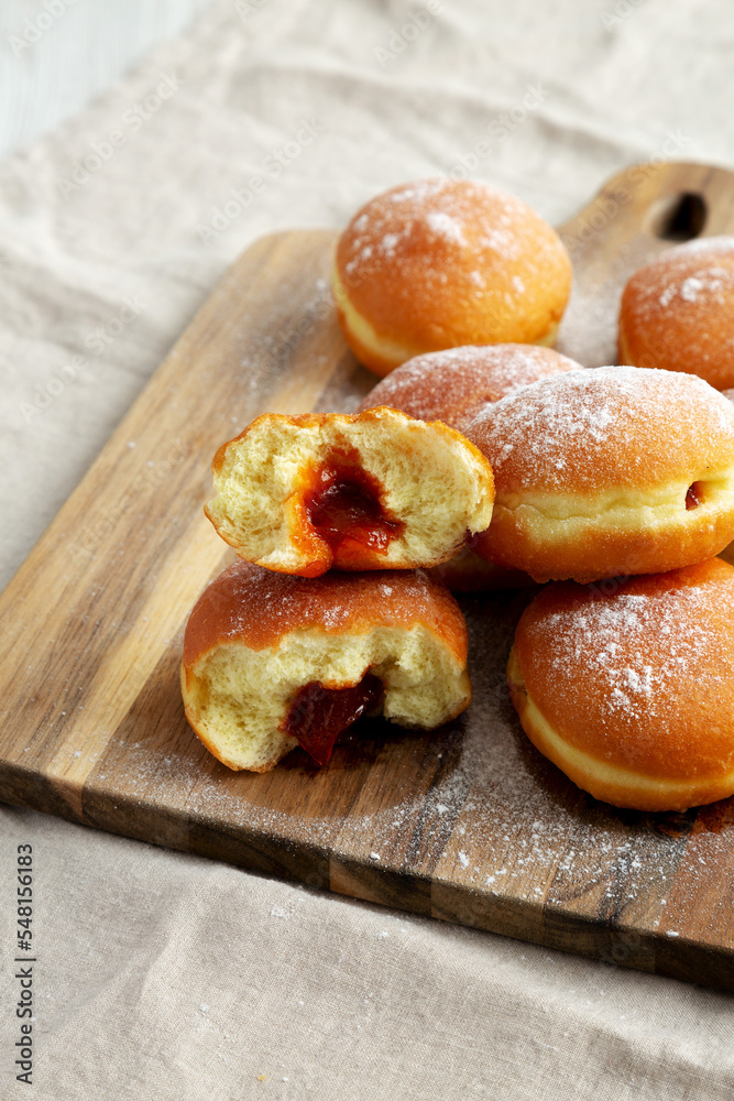 Homemade Apricot Polish Paczki Donut with Powdered Sugar on a Wooden Board, side view. Close-up.