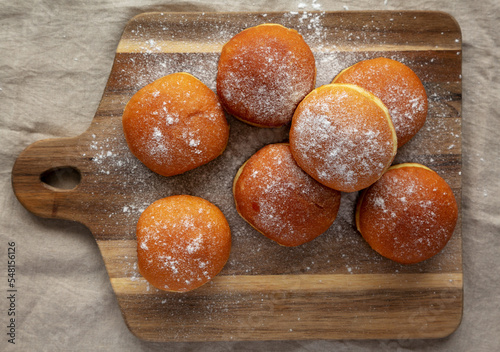 Photo Homemade Apricot Polish Paczki Donut with Powdered Sugar on a Wooden Board, top view
