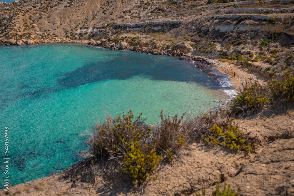 One of the many beautiful beaches in Malta, nice bay with sandy and rocky beach in the mediterranean.