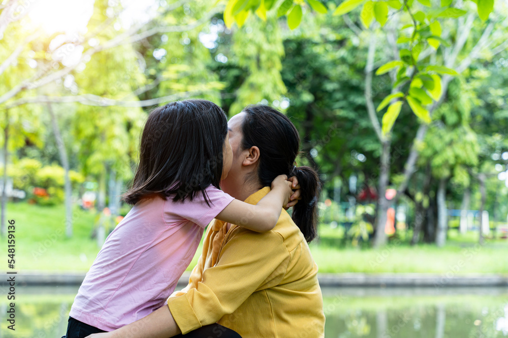 Cute young daughter with her mother hugging in love playing together in a park Cute young daughter with her mother hugging in love playing together in a park