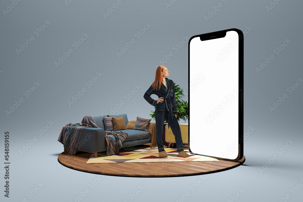 Young girl in homewear standing near to 3d model of cellphone with blank white screen and dreaming isolated on grey background. Online shopping, payment, new app or website - obrazy, fototapety, plakaty 