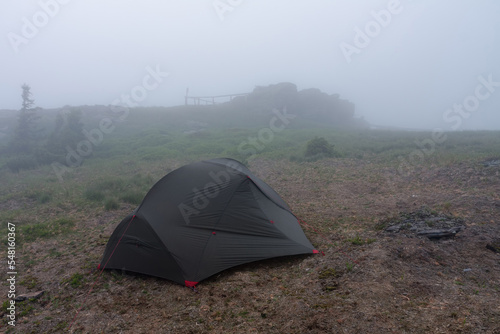Green lightweight freestanding three-season 2-person tent on  hill in grass in the evening after rainstorm.  Jesenik mountains  Czech Republic