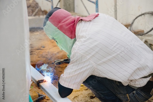 construction man is welding steel roof structure, people working in construction site concept