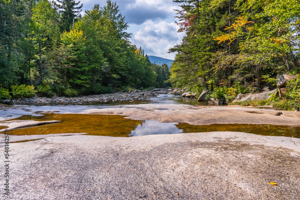 Obraz premium Smooth, glacially chiseled boulders in the Ammonoosuk Riverbed, surrounded by forests near Mount Washington in New Hampshire's White Mountain National Forest.