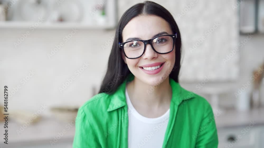 Close up face of smiling young attractive woman with eyeglasses looking at camera at light living room. head shot Portrait of happy beautiful female in green shirt indoors at home Close up face of smiling young attractive woman with eyeglasses looking at camera at light living room. head shot Portrait of happy beautiful female in green shirt indoors at home
