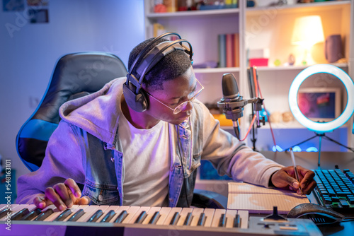 Black man artist recording music while playing electronic piano at home studio.. Creative songwriter man sit at table. High quality photo