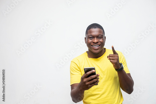 Recommendation. Portrait of excited black guy holding smartphone pointing up looking camera