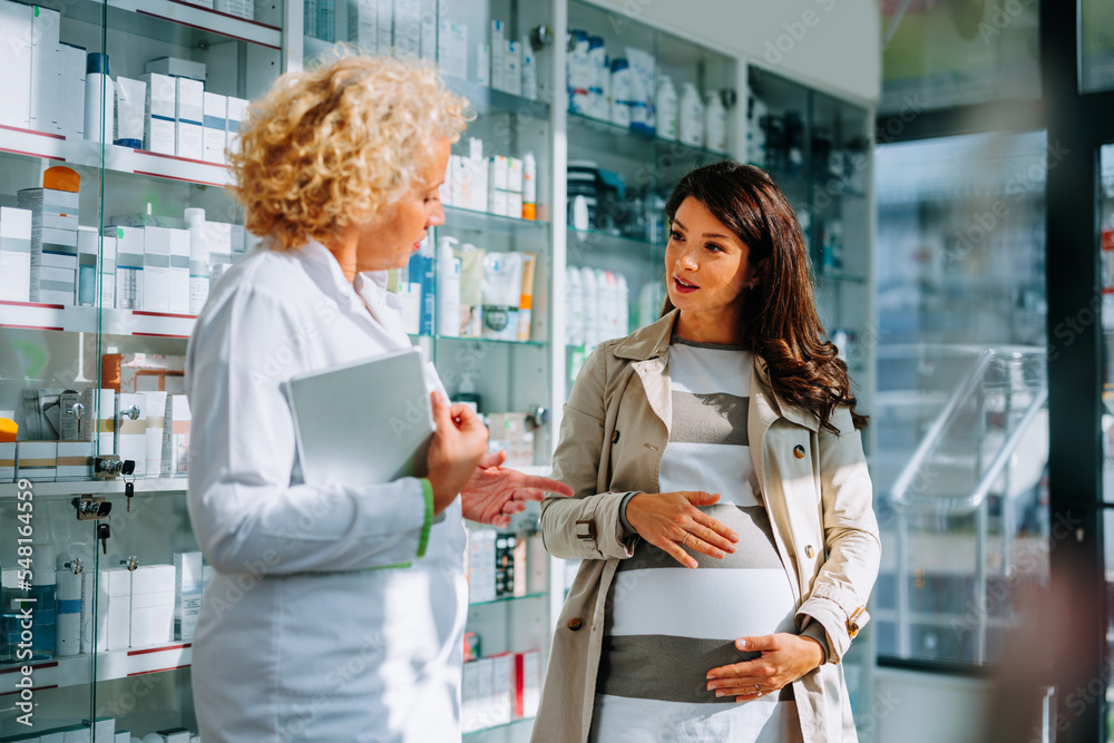 Expecting woman talking to pharmacist. Expecting woman talking to pharmacist.