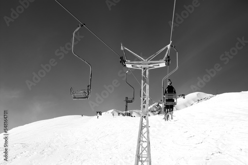 Black and white view on old chair-lift and off-piste slope at ski resort