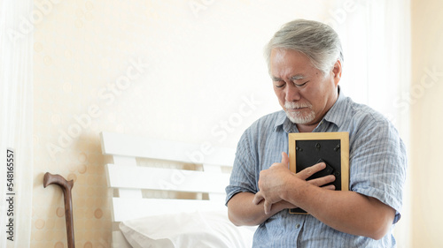 Фотография Senior male unhappy is crying, hugging the image of the deceased wife, remember