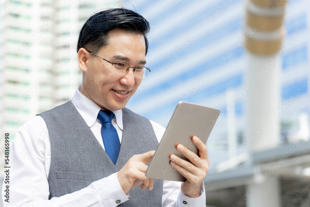 Business Asian man using tablet computer on business district urban - lifestyle business people concept Business Asian man using tablet computer on business district urban - lifestyle business people concept