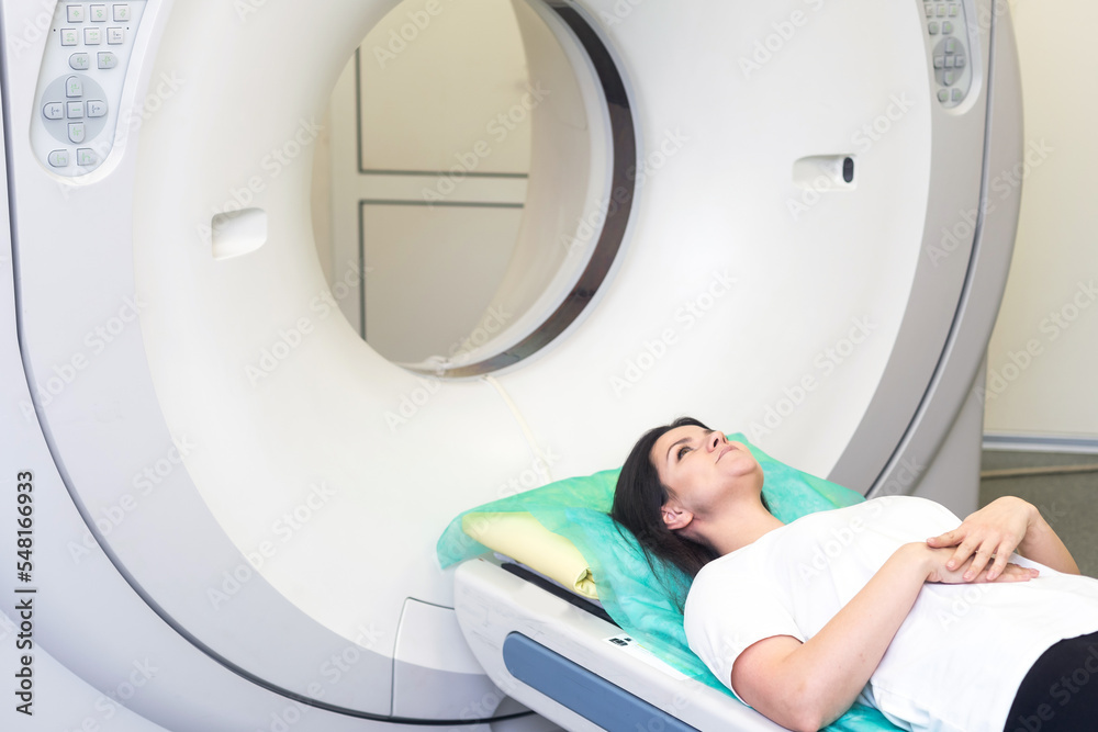 CT scan technologist overlooking patient in Computed Tomography scanner during preparation for procedure. Woman patient going into CT scanner. CT scan technologist overlooking patient in Computed Tomography scanner during preparation for procedure. Woman patient going into CT scanner.