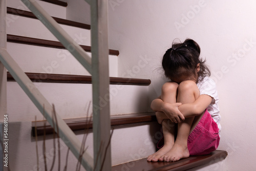 Adorable asian girl who expresses her sadness emotion on house stair alone shows concept of depression, emotional pain and unhappiness of child which might due to abusement from family and school.
