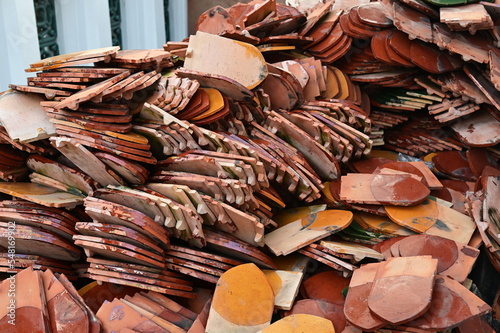 Terracotta roof tiles(roof clay tiles) shaped like lotus petals or fish scales, painted in orange and brown, are stacked together to wait for roofing of pavilions, churches in temples or ancient house