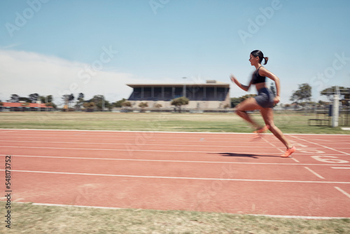 Woman, fast runner and sports on stadium track for marathon training or exercise wellness. Athlete person, motion blur and running workout or fitness cardio, energy and speed or race performance
