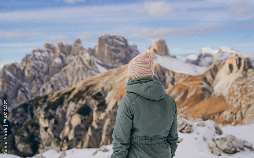 Young girl enjoying beauty of nature looking at mountain in Dolomites. Adventure travel in Italy, Europe. Travel and dream vacation concept. High rocks, winter landscape Young girl enjoying beauty of nature looking at mountain in Dolomites. Adventure travel in Italy, Europe. Travel and dream vacation concept. High rocks, winter landscape