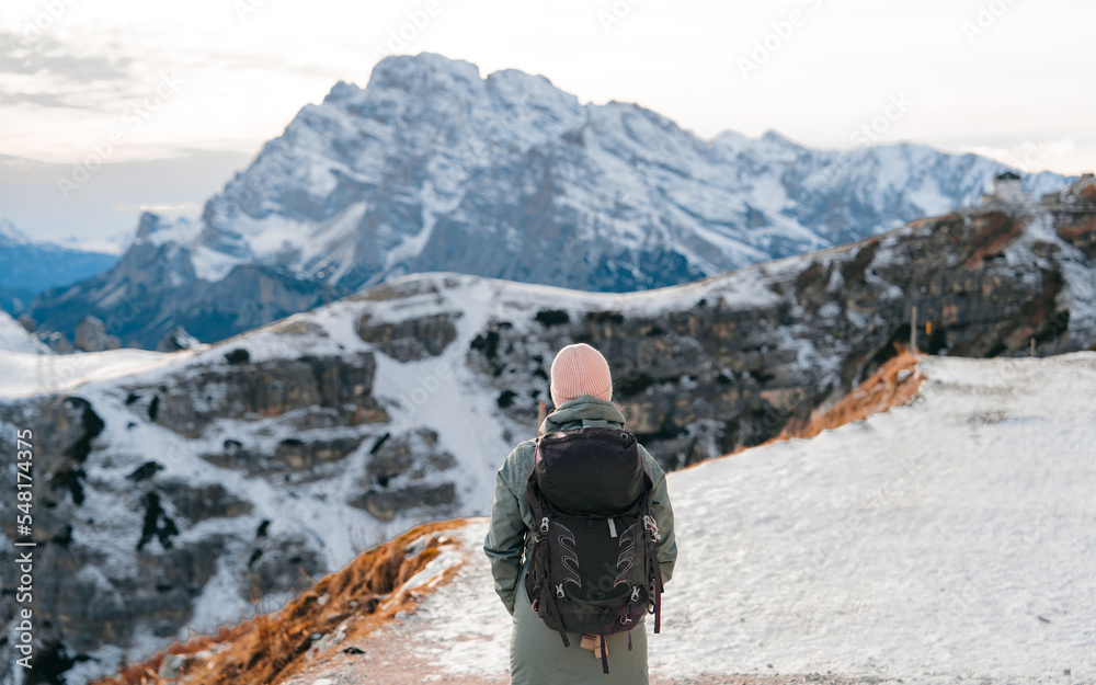 Young girl enjoying beauty of nature looking at mountain in Dolomites. Adventure travel in Italy, Europe. Travel and dream vacation concept. High rocks, winter landscape