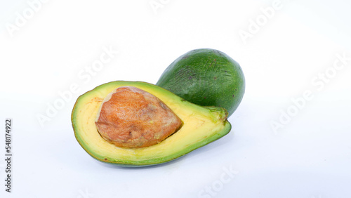 Green avocado fruit that has been split and is ripe. Contains many vitamins for human health. Placed on a white mat.
