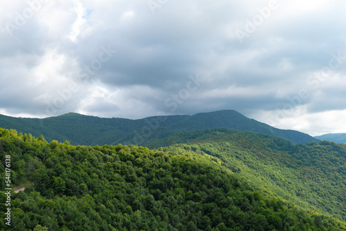 mountain in the stormy cloudy sky, road through mountain. dark clouds over scenic forested hills